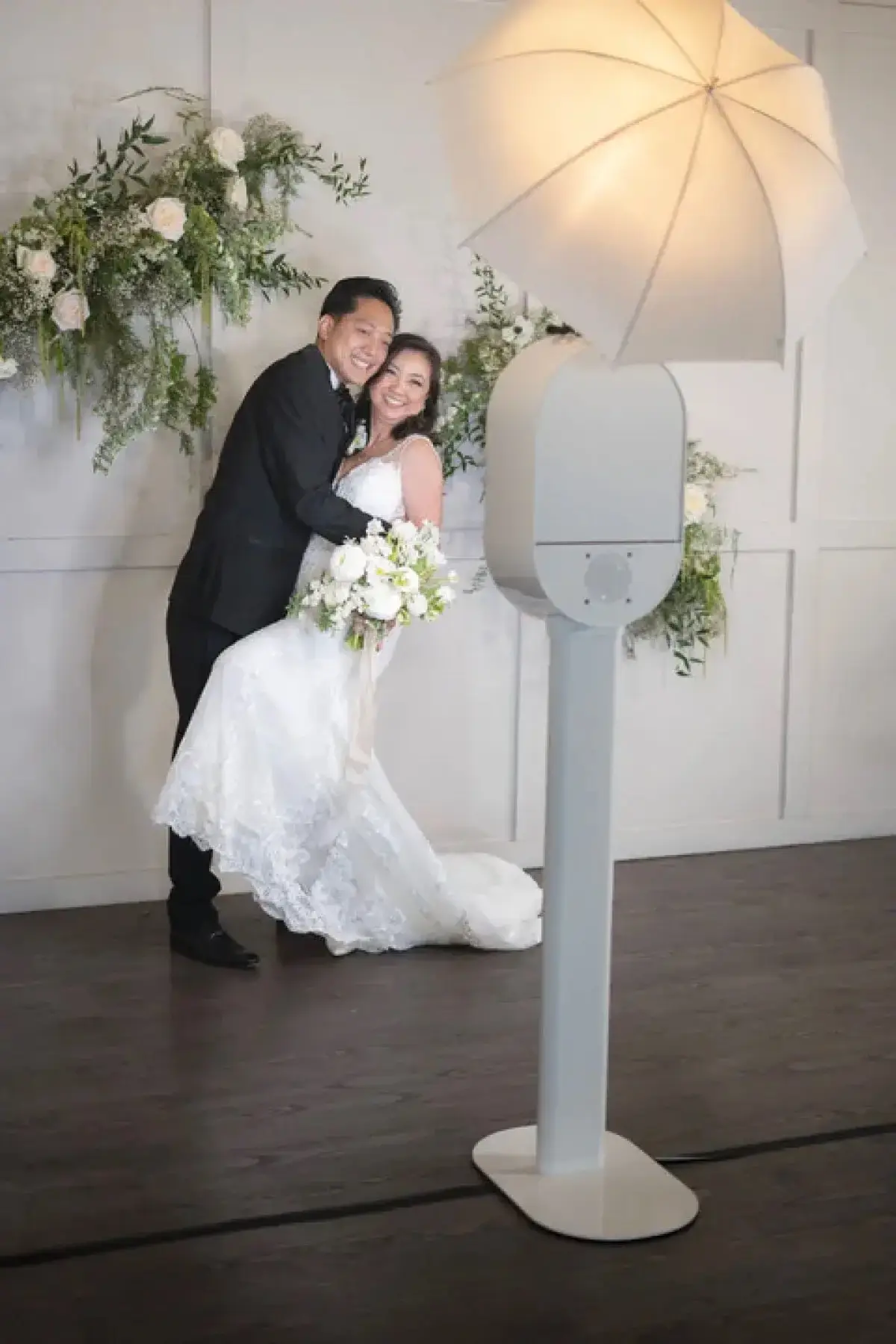 Bride and groom posing in front of a white photo booth